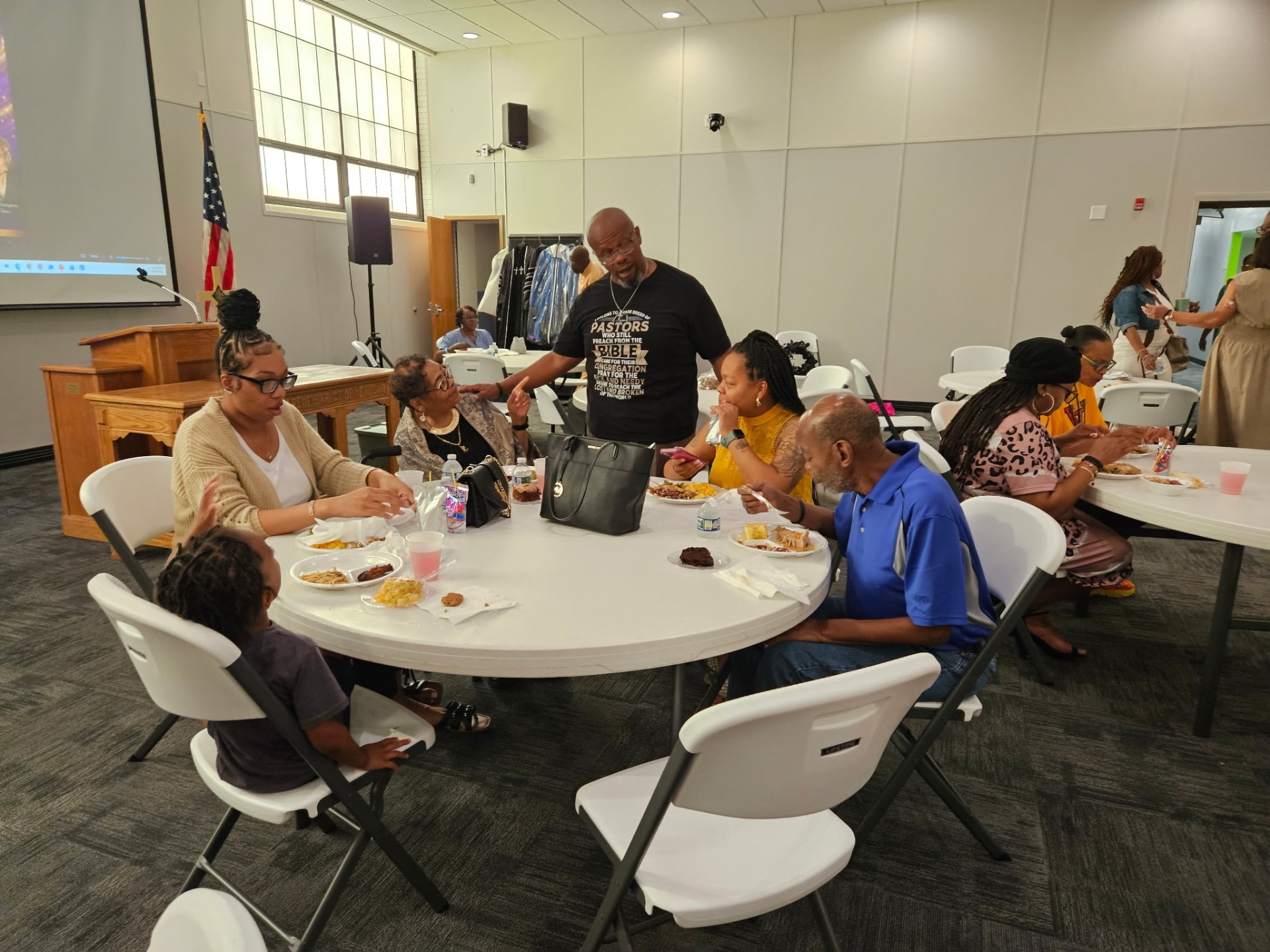 Families gathered around tables sharing a meal in the fellowship hall